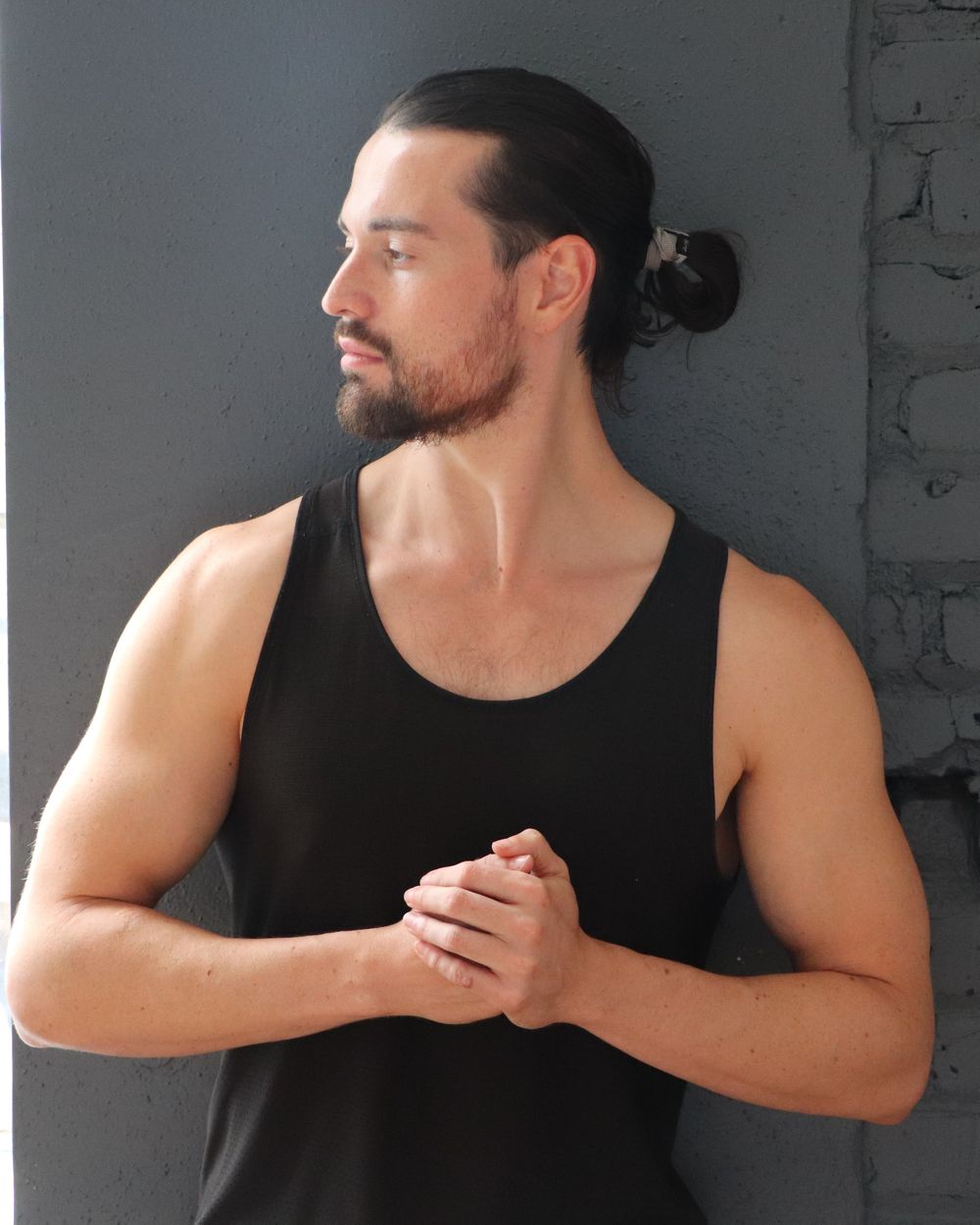 Anthony standing with hands clasped, looking aside